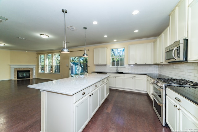 kitchen with dark hardwood / wood-style flooring, a kitchen island, pendant lighting, and appliances with stainless steel finishes