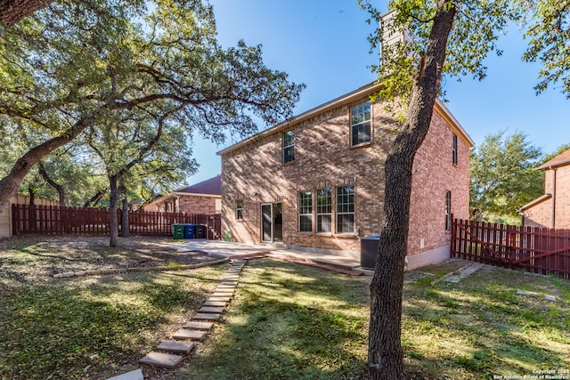 rear view of house with a lawn, central AC, and a patio