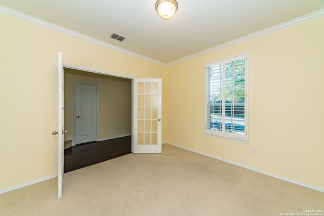 spare room with french doors, light colored carpet, and ornamental molding