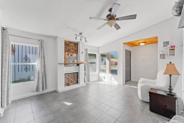 tiled living room featuring a textured ceiling, a brick fireplace, ceiling fan, and lofted ceiling