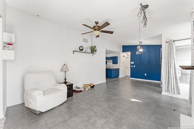 living area featuring tile patterned floors, ceiling fan, and a textured ceiling