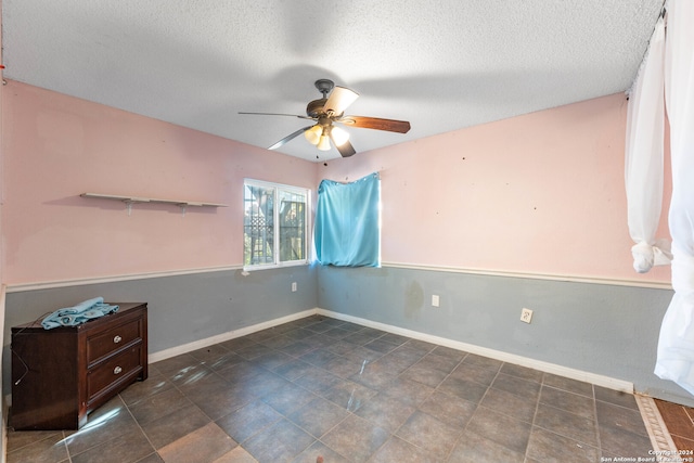 empty room with ceiling fan and a textured ceiling