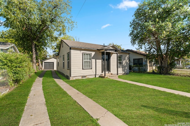 bungalow-style house featuring a front yard, a garage, and an outdoor structure