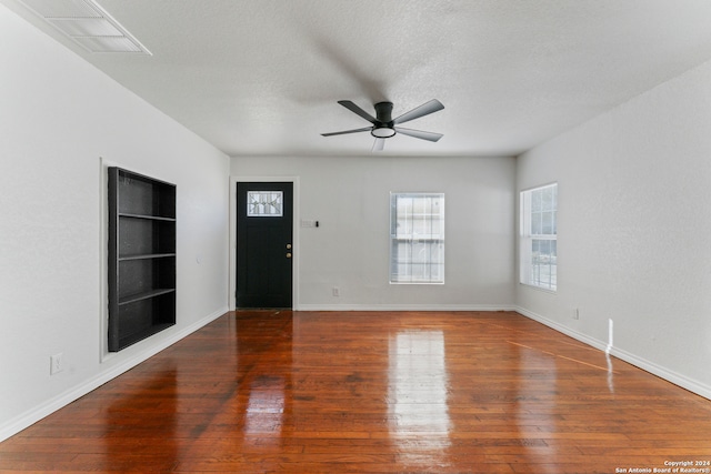 interior space featuring a textured ceiling, dark hardwood / wood-style floors, built in features, and ceiling fan