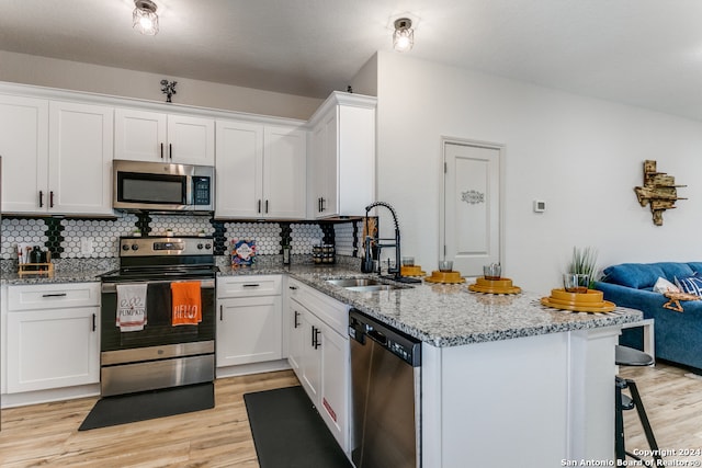 kitchen featuring tasteful backsplash, white cabinetry, light hardwood / wood-style flooring, and appliances with stainless steel finishes