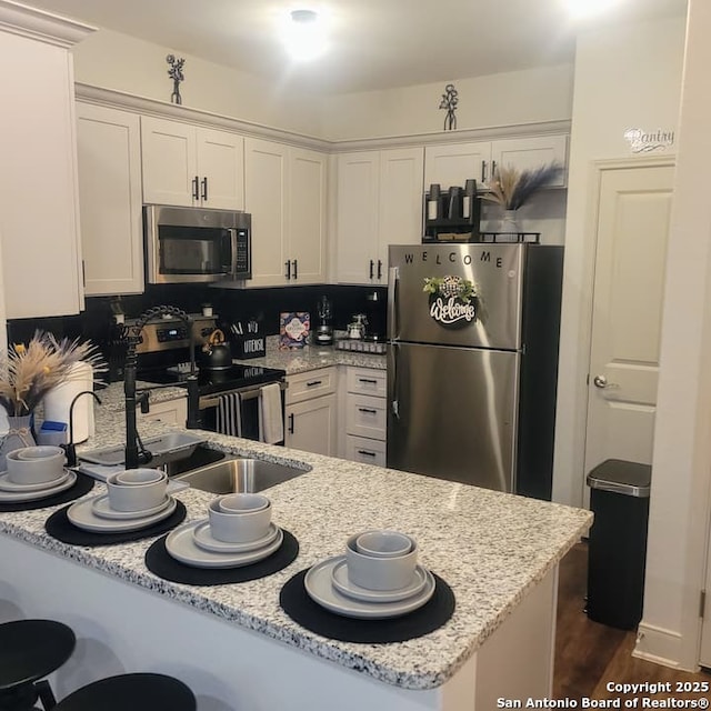 kitchen with decorative backsplash, light stone counters, white cabinets, and stainless steel appliances