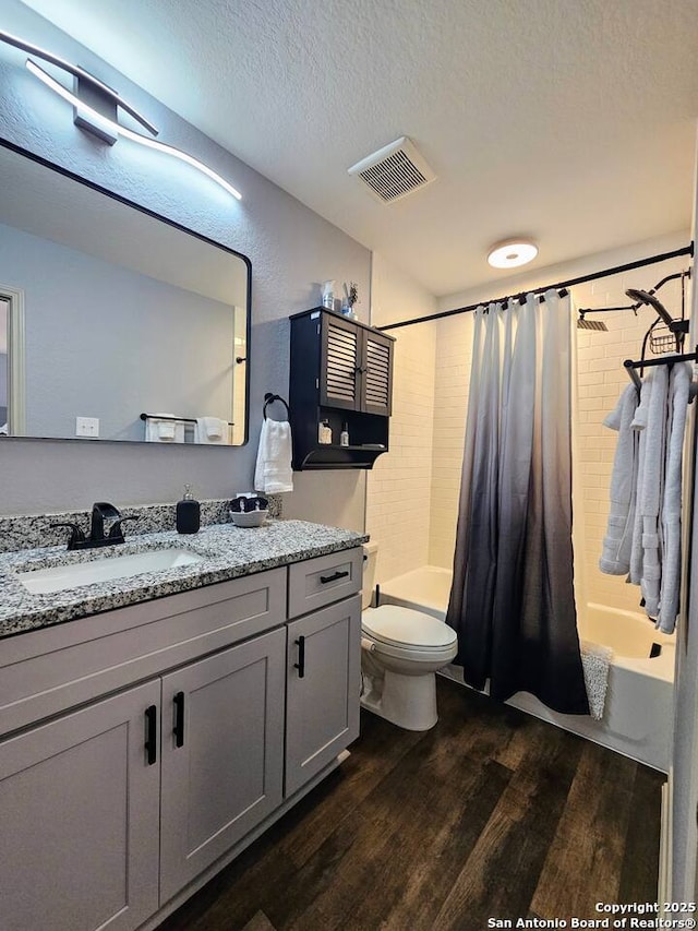 full bathroom featuring a textured ceiling, vanity, shower / bathtub combination with curtain, hardwood / wood-style floors, and toilet