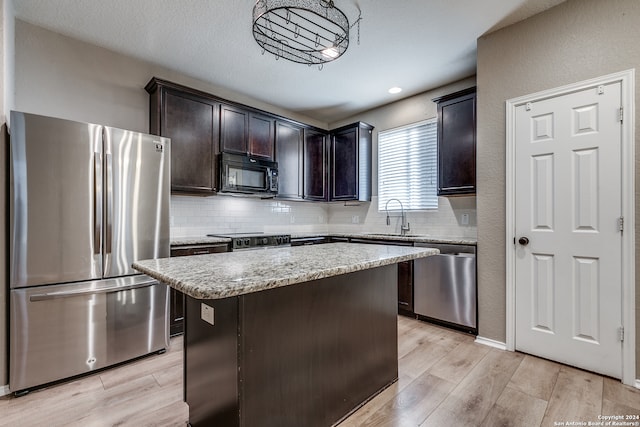 kitchen with a center island, sink, hanging light fixtures, stainless steel appliances, and light hardwood / wood-style flooring