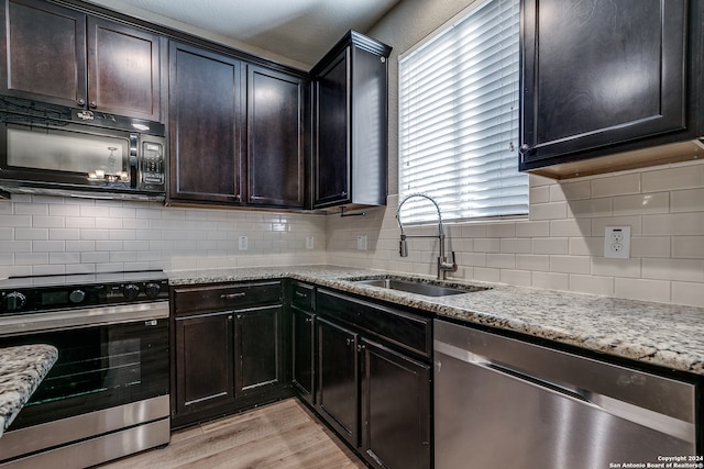 kitchen featuring sink, light stone countertops, stainless steel appliances, and light hardwood / wood-style flooring