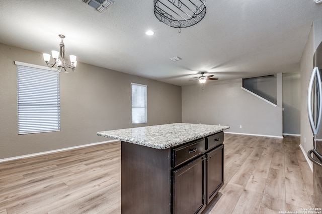 kitchen featuring pendant lighting, a center island, ceiling fan with notable chandelier, light hardwood / wood-style floors, and dark brown cabinetry