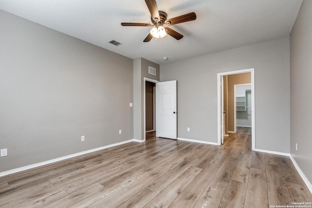 11902 Silver Horse, San Antonio, TX 78254 - unfurnished bedroom featuring light wood finished floors, baseboards, ceiling fan, and a walk in closet