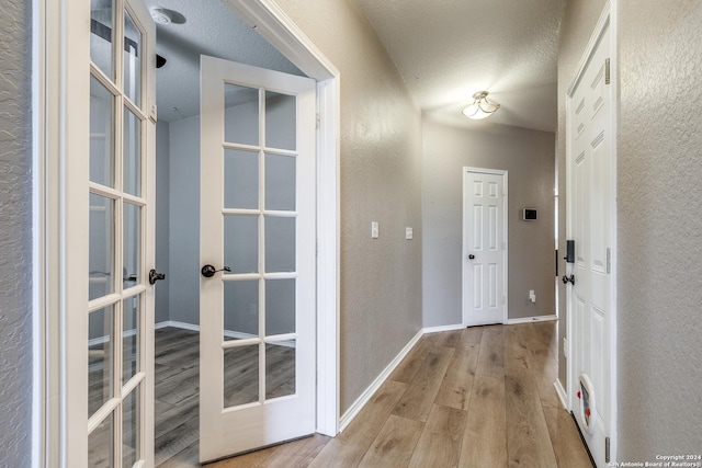 11902 Silver Horse, San Antonio, TX 78254 - hall with french doors, wood finished floors, a textured wall, baseboards, and a textured ceiling