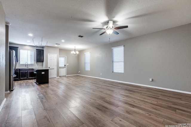 11902 Silver Horse, San Antonio, TX 78254 - unfurnished living room featuring a ceiling fan, a chandelier, a sink, light wood-style flooring, and a textured ceiling