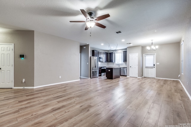 unfurnished living room with ceiling fan with notable chandelier, a textured ceiling, light wood-type flooring, and sink