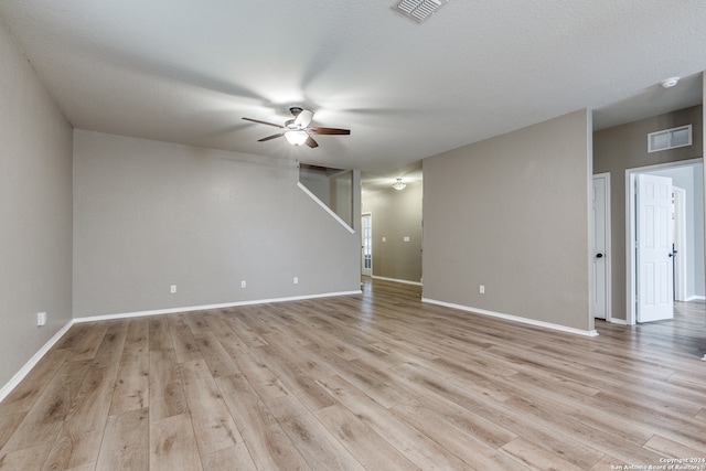 empty room with ceiling fan, light wood-type flooring, and a textured ceiling