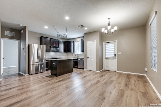 kitchen with decorative light fixtures, a kitchen island, a notable chandelier, light hardwood / wood-style floors, and stainless steel appliances