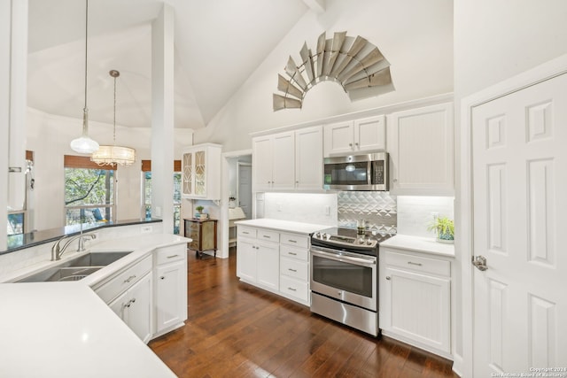 kitchen with appliances with stainless steel finishes, dark hardwood / wood-style flooring, pendant lighting, high vaulted ceiling, and white cabinets