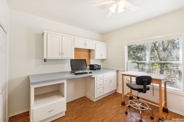 office space with ceiling fan, plenty of natural light, built in desk, and light hardwood / wood-style floors