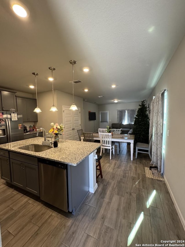 14534 Prairie Clover, San Antonio, TX 78253 - kitchen with appliances with stainless steel finishes, a sink, dark wood-type flooring, a center island with sink, and light stone counters