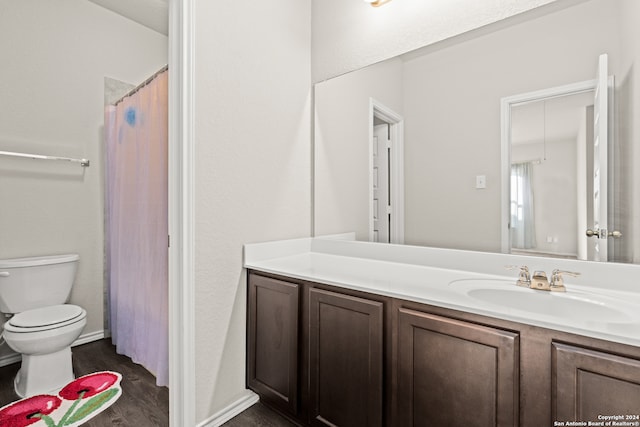 bathroom with wood-type flooring, vanity, toilet, and walk in shower