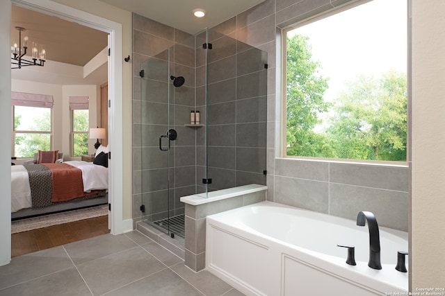 bathroom with tile patterned flooring, plus walk in shower, a wealth of natural light, and an inviting chandelier