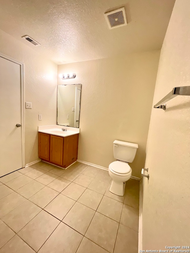 bathroom with tile patterned flooring, vanity, a textured ceiling, and toilet