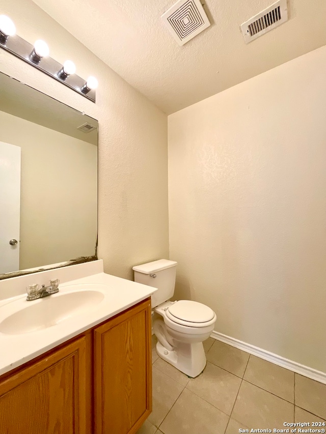 bathroom featuring tile patterned flooring, a textured ceiling, vanity, and toilet