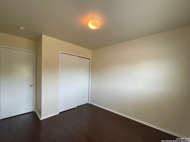 unfurnished bedroom with dark hardwood / wood-style flooring and a closet