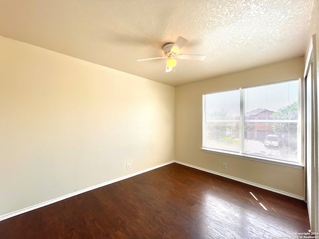 empty room featuring ceiling fan, dark wood-type flooring, and a textured ceiling