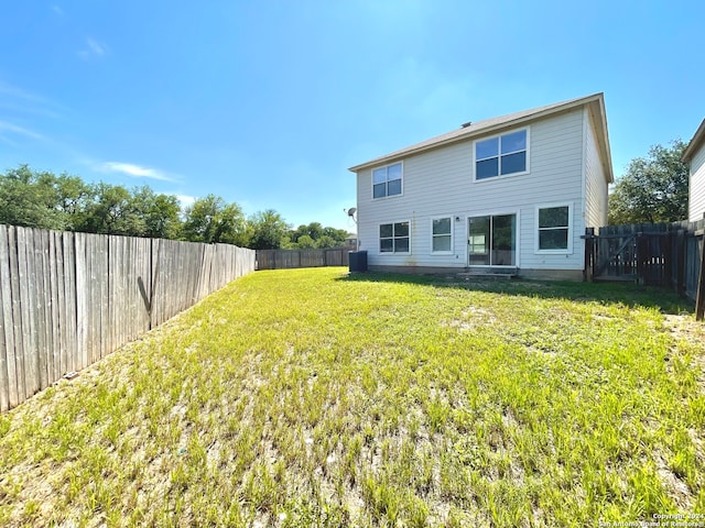 rear view of property with a yard and central AC unit