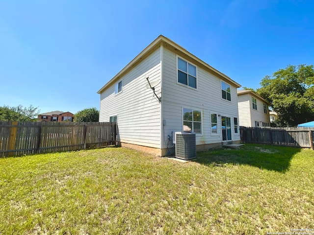 rear view of house with central AC and a lawn