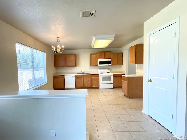 kitchen featuring white appliances, sink, light tile patterned floors, decorative light fixtures, and a chandelier