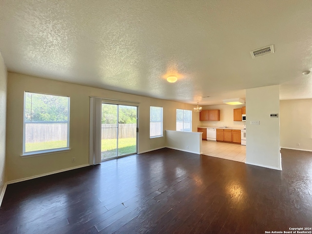 unfurnished living room featuring light wood-type flooring, a textured ceiling, and an inviting chandelier