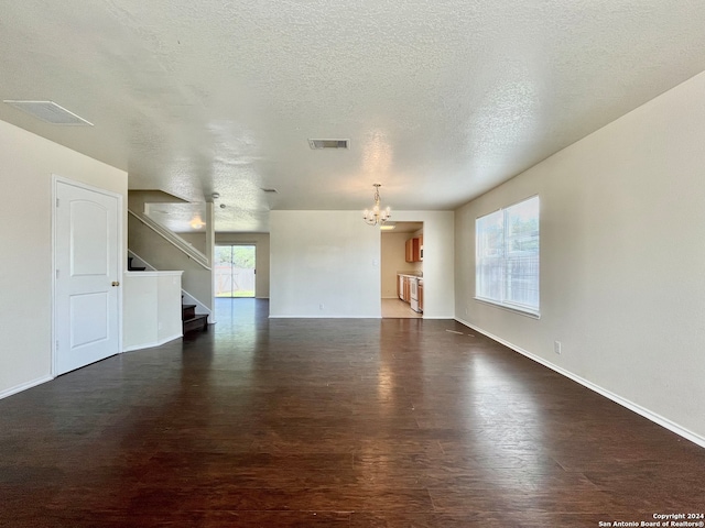 unfurnished room with a textured ceiling, dark hardwood / wood-style flooring, and an inviting chandelier