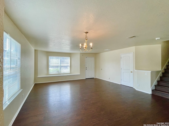 empty room featuring dark hardwood / wood-style floors, a textured ceiling, and an inviting chandelier