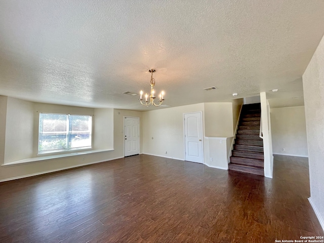 unfurnished living room with a textured ceiling, dark hardwood / wood-style floors, and an inviting chandelier