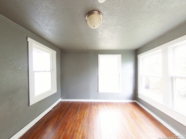 unfurnished room featuring a textured ceiling and hardwood / wood-style flooring