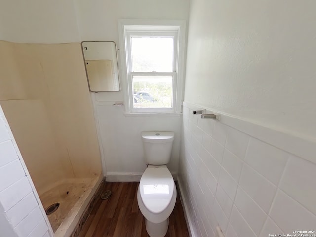 bathroom with walk in shower, toilet, tile walls, and hardwood / wood-style flooring