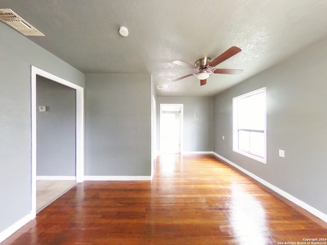 empty room featuring ceiling fan, wood-type flooring, and a textured ceiling