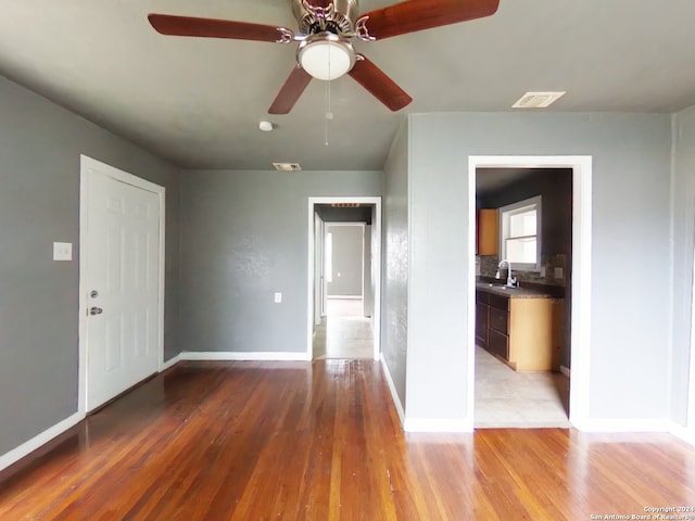 unfurnished room featuring light hardwood / wood-style floors, ceiling fan, and sink