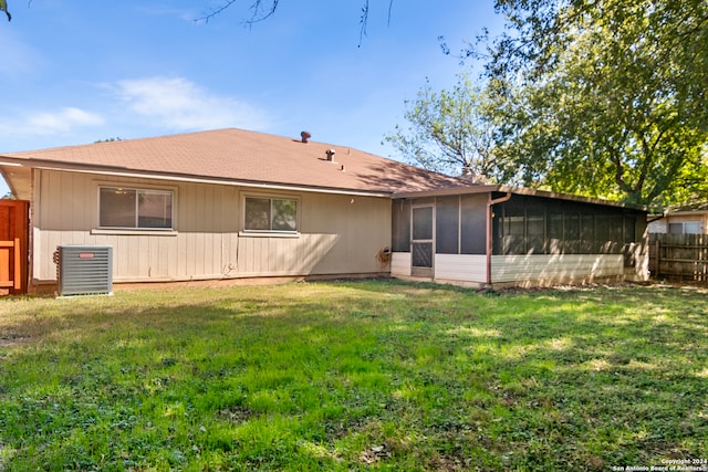 rear view of house featuring central AC unit, a sunroom, and a lawn