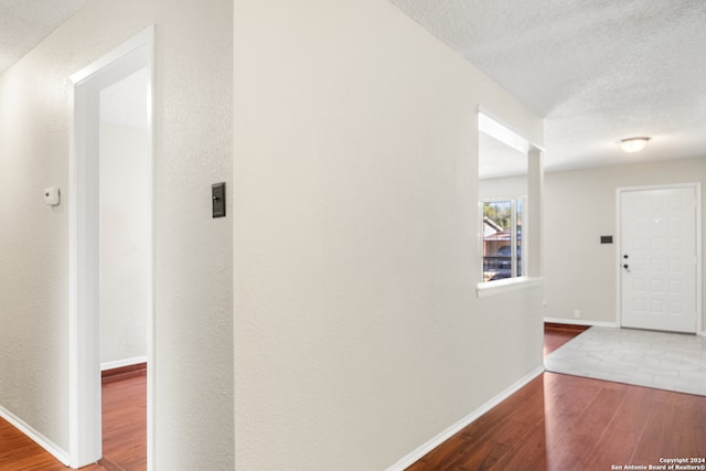 hallway with wood-type flooring and a textured ceiling