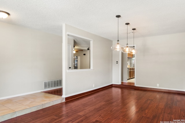 empty room with a textured ceiling, hardwood / wood-style flooring, and ceiling fan