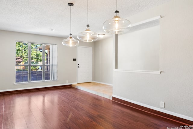 unfurnished room with hardwood / wood-style floors and a textured ceiling