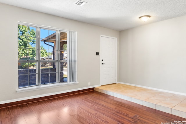 unfurnished room with a textured ceiling and hardwood / wood-style flooring