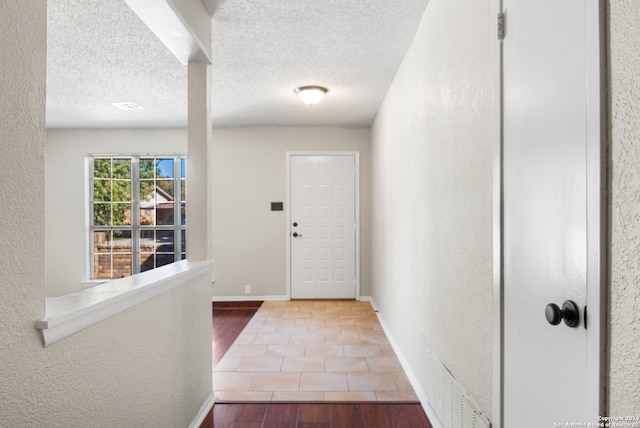 doorway to outside with wood-type flooring and a textured ceiling