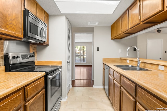 kitchen with sink, light tile patterned floors, backsplash, and appliances with stainless steel finishes