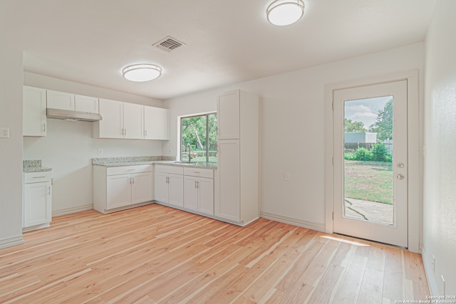 kitchen featuring light wood-type flooring, white cabinetry, plenty of natural light, and sink