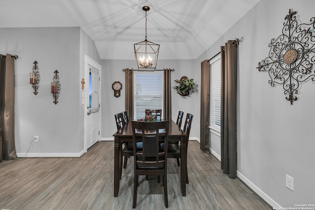 dining room with a chandelier, hardwood / wood-style flooring, and lofted ceiling