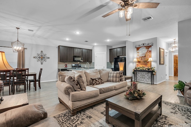 living room featuring sink, ceiling fan with notable chandelier, and light wood-type flooring